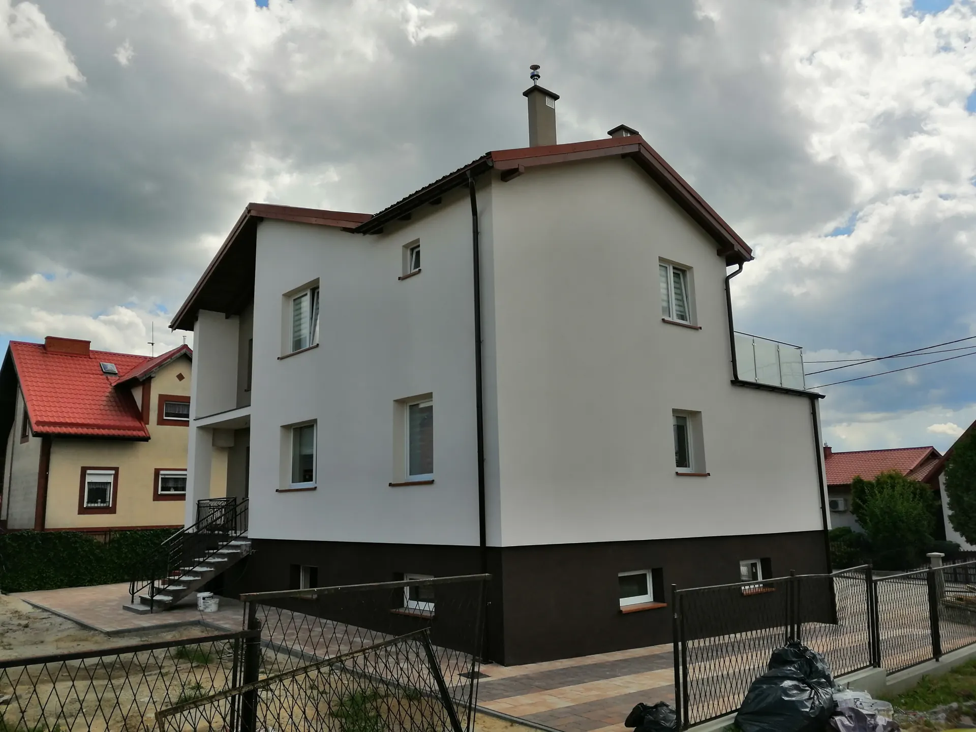 Elewacja domu z nowym, ciemnym cokołem po pracach izolacyjnych