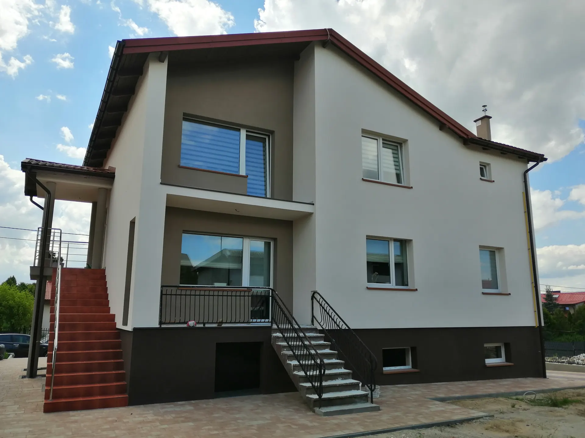 Ten sam dom po dociepleniu, z jasną elewacją i ciemnym cokołem